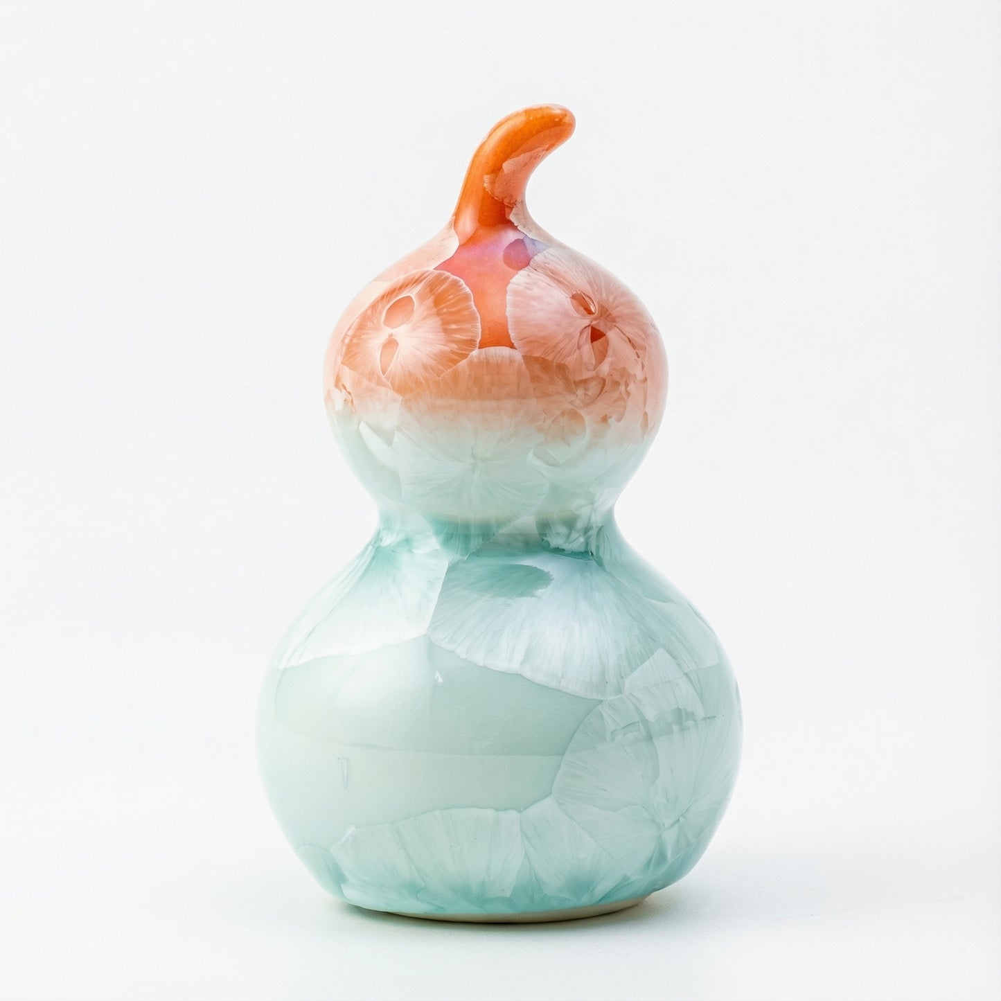 A small ceramic gourd with a vibrant coral orange and white crystalline glaze.
