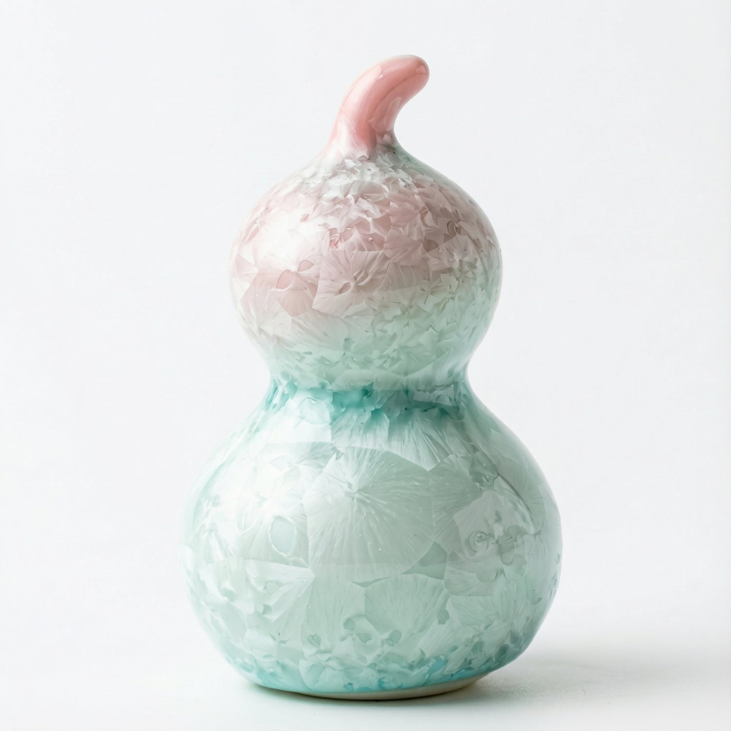 A small ceramic gourd with a delicate pastel pink crystalline glaze