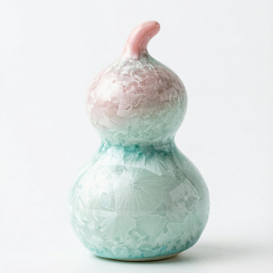 A small ceramic gourd with a delicate pastel pink crystalline glaze
