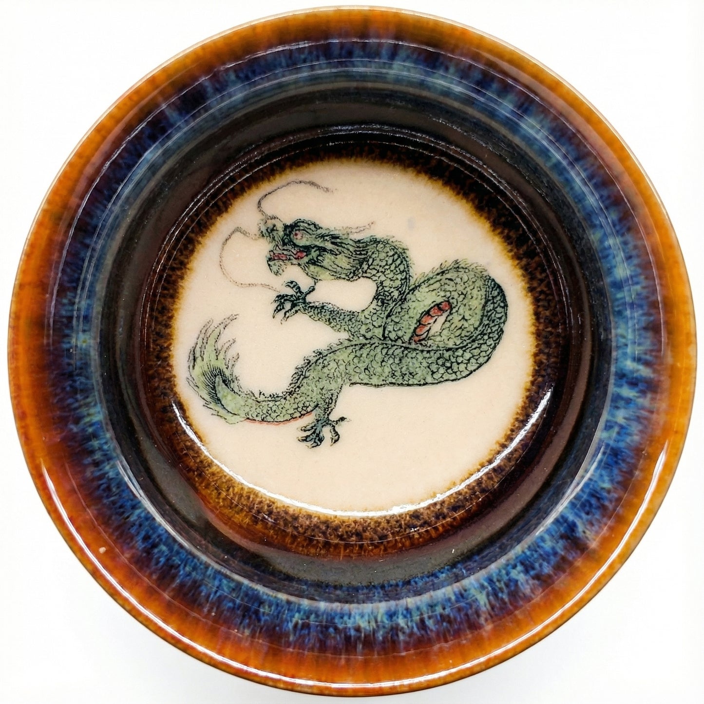 Handmade ceramic tea bowl featuring a hand-painted green dragon and blue glaze finish.