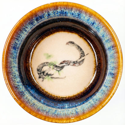 Unique ceramic tea bowl with a coiled Snake design, featuring a classic Tenmoku-style finish.